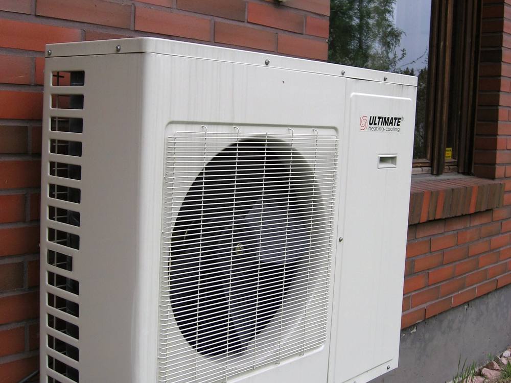 Unidad exterior de una bomba de calor aerotérmica instalada junto a la fachada de un edificio