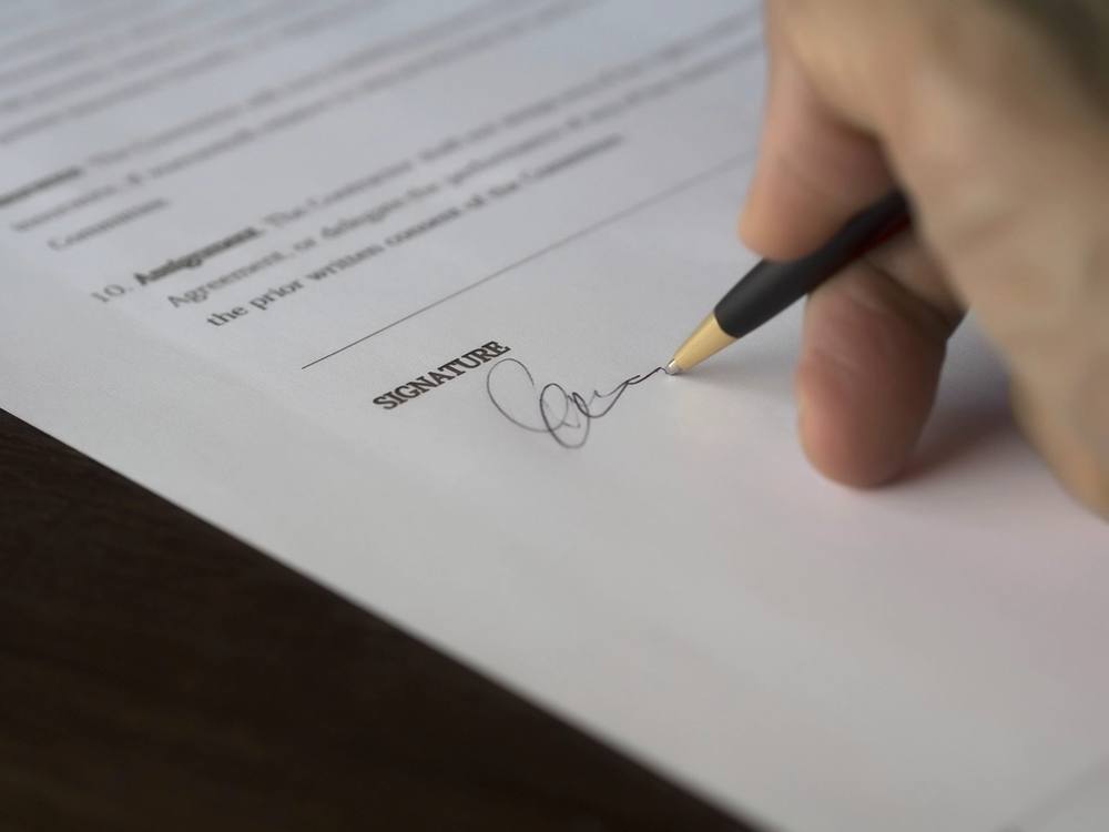 Persona firmando un documento sobre una mesa